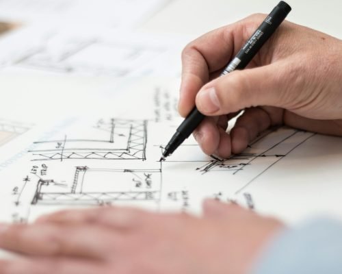 Close-up of hand drawing intricate technical designs on blueprint with pen, ideal for engineering or architecture themes.